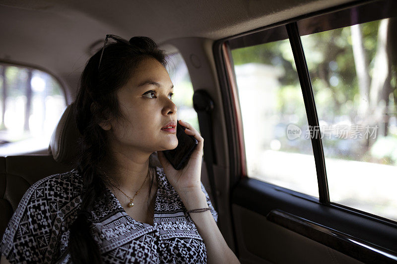亚洲女性在乘出租车时使用手机