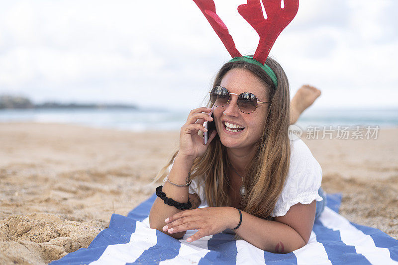 圣诞节的时候，一个女人一边在海滩上晒太阳一边打电话