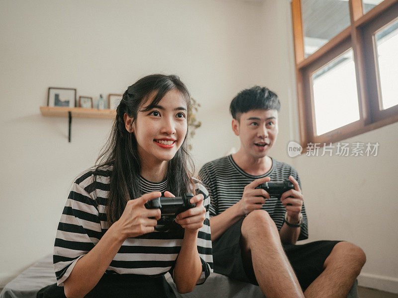 亚洲家庭在家里玩电子游戏。
