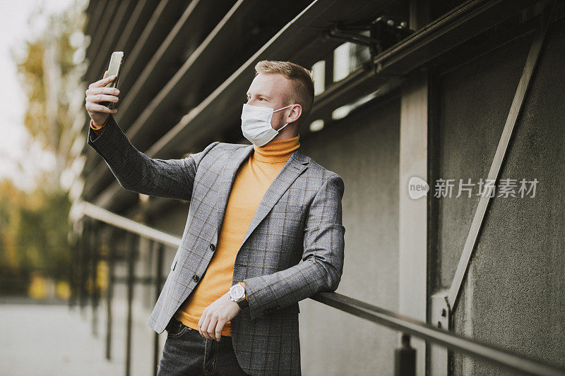 一名商人在冠状病毒大流行期间使用手机并佩戴防护口罩