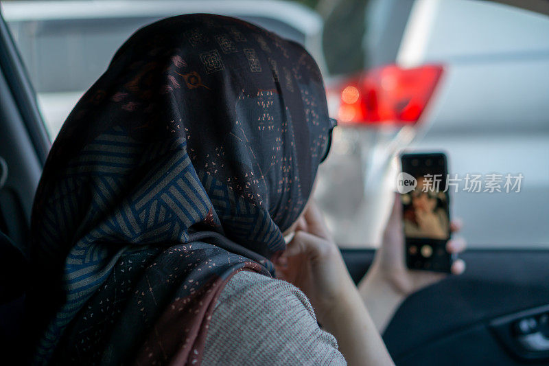 亚洲女性准备在车里通过智能手机进行直播