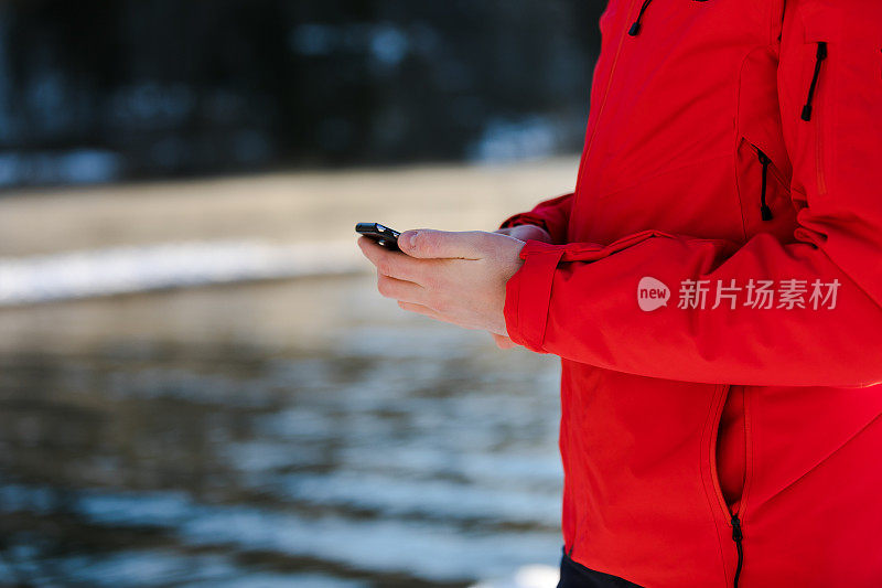 一名男子在湖边使用智能手机。