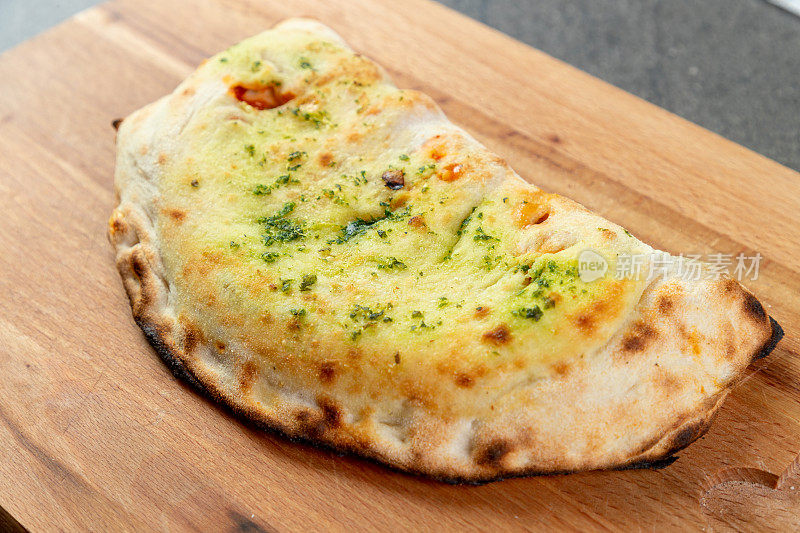加罗勒调味的Calzone披萨放在木板上