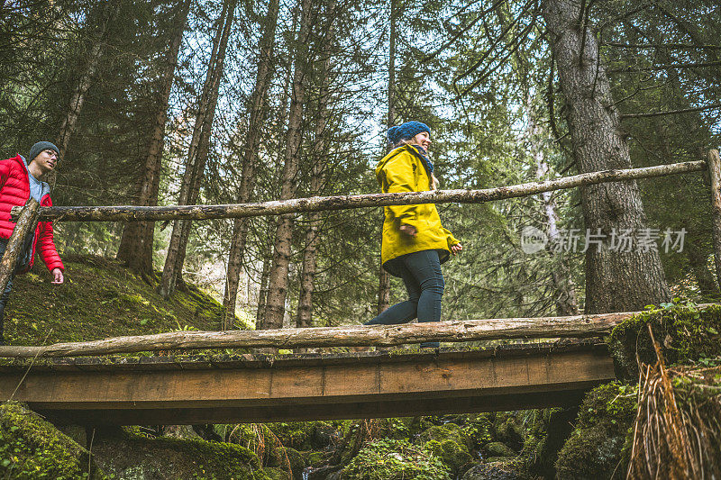一对年轻的徒步旅行者穿过森林中的一座桥