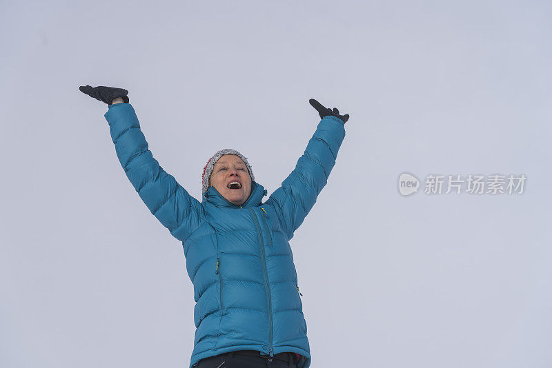 成熟的女人穿着皮大衣，双手举向天空