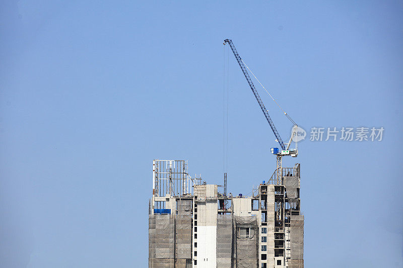 高层商业大厦正在建设中，顶部装有动力起重机