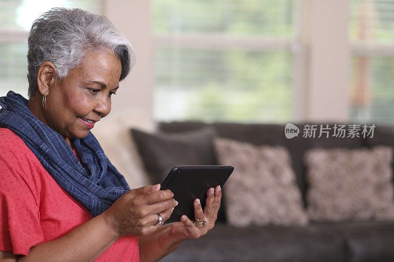 成年妇女在家里使用数字平板电脑。