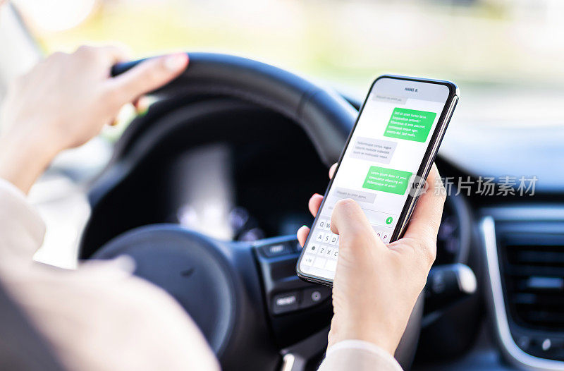 开车和使用电话。分心的司机用手机发短信。交通堵塞时用智能手机查看短信的不负责任的女人。汽车事故的概念。