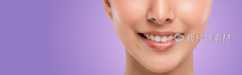 靠近脸部的一部分。带着笑脸的白种人少女完美整齐的牙齿。孤立的紫色。