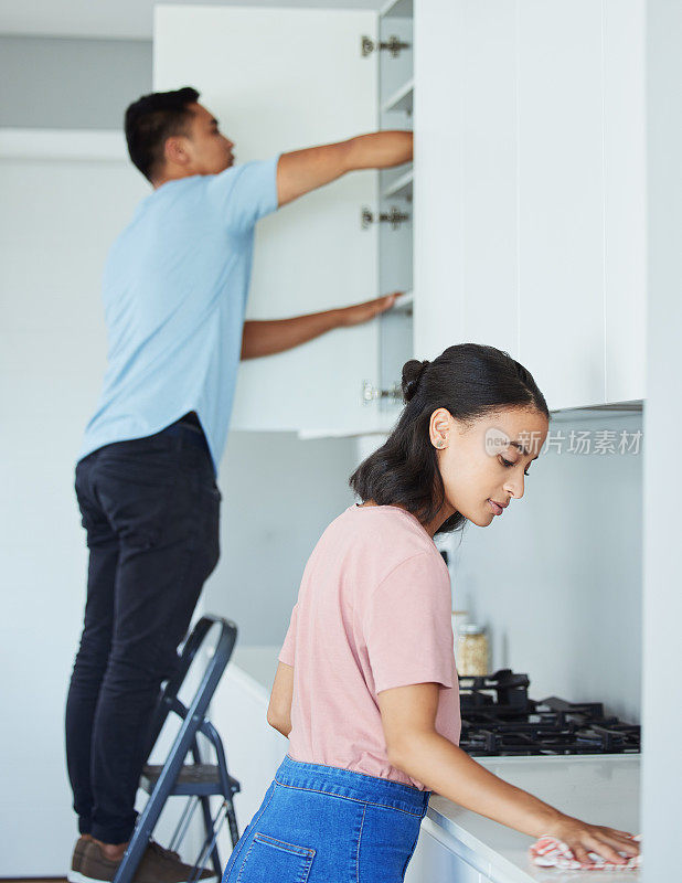 一对年轻夫妇一起打扫厨房的照片