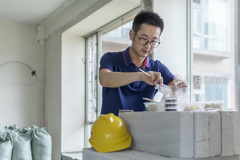 亚洲男工程师在装修工地吃外卖