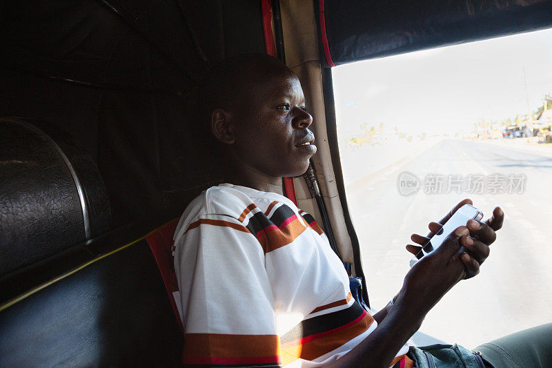 年轻的非洲男子在出租车内使用手机