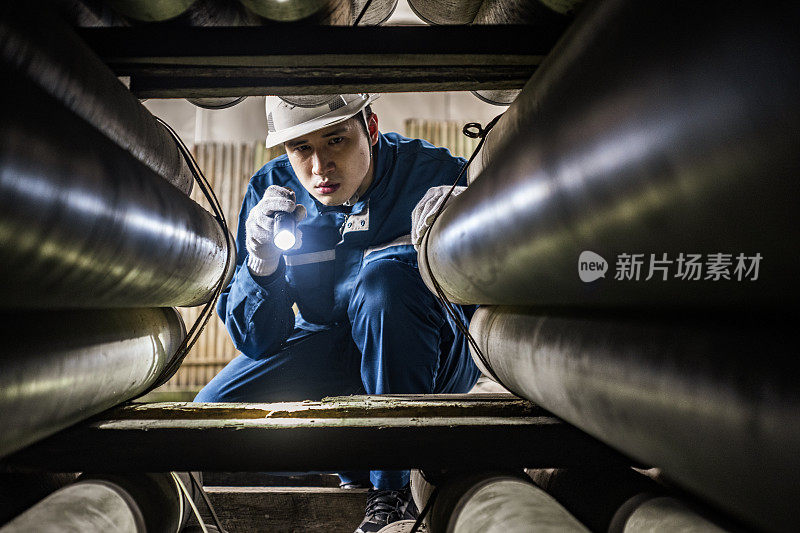 蓝领工人用手电筒检查管道