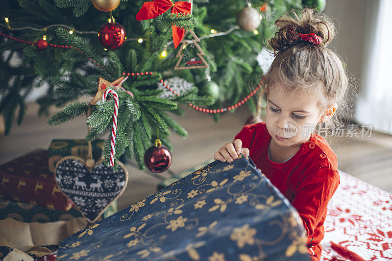 可爱的小孩在圣诞树旁打开礼物