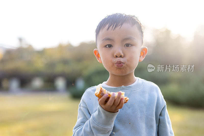 一个男孩正在户外吃面包