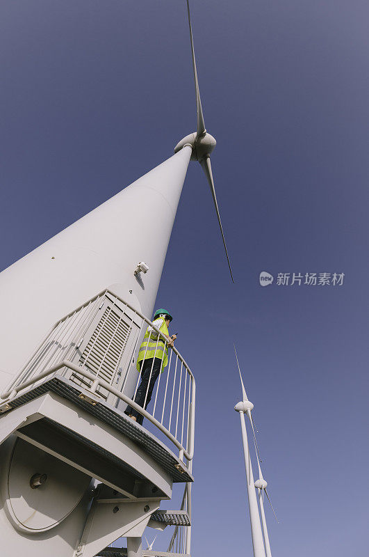 年轻的女工程师正在现场检查风力涡轮机