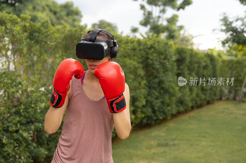 年轻的拳击手妇女戴着虚拟现实头盔在公园里练习。