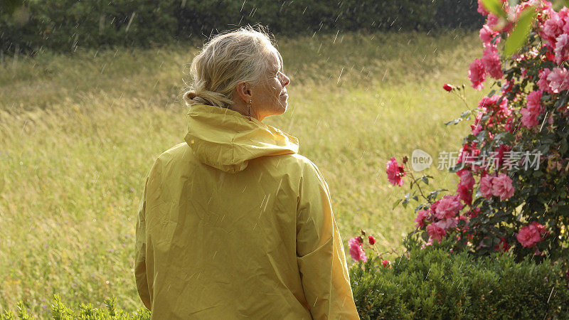 女人拥抱着细雨，在郁郁葱葱的草地上