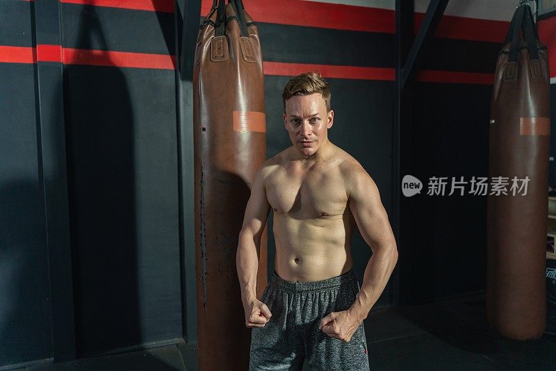 年轻英俊的男性拳击手，肌肉发达的身体自豪地展示他的身体肌肉在健身房