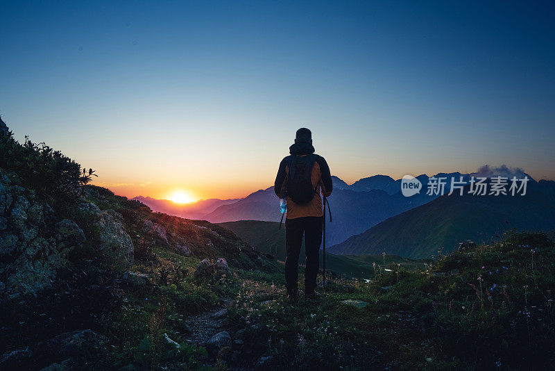 日落时在山上的徒步旅行者的剪影