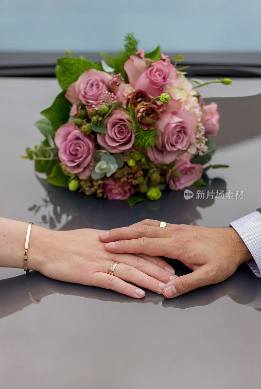 垂直拍摄的新婚新娘和新郎手牵着手旁边的一束花