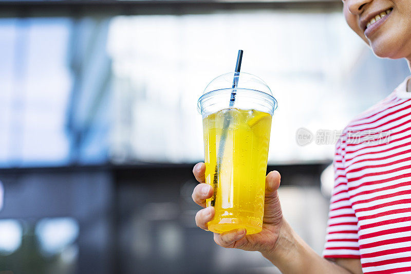 用塑料杯盛着柠檬水的女人的手