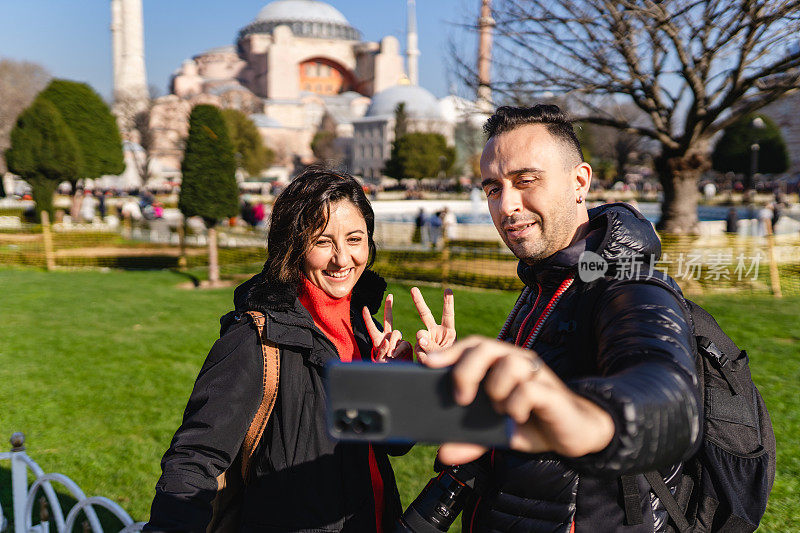 年轻的游客夫妇在圣索菲亚清真寺拍照