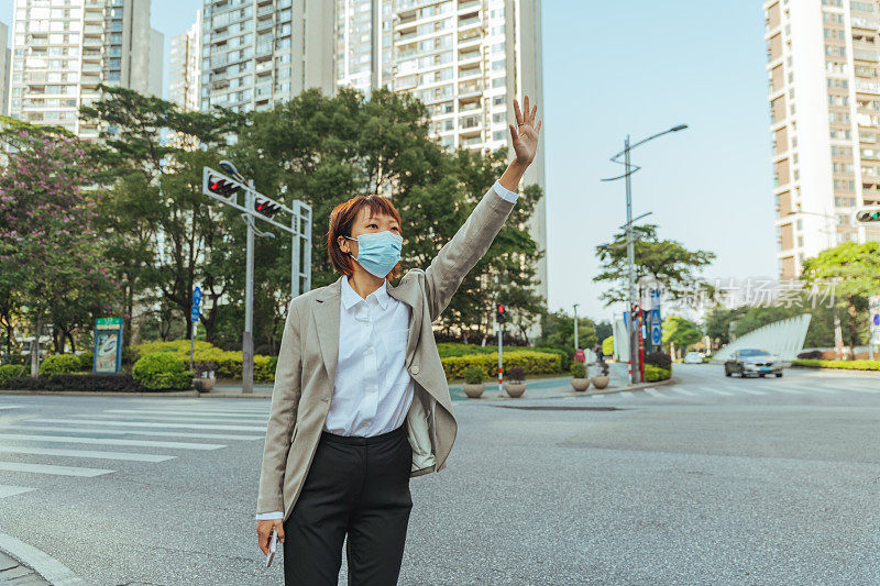 在城市街道上挥手招呼出租车的妇女