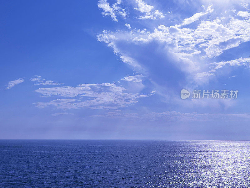 天空的云彩映在闪闪发亮的蓝色海水上。
