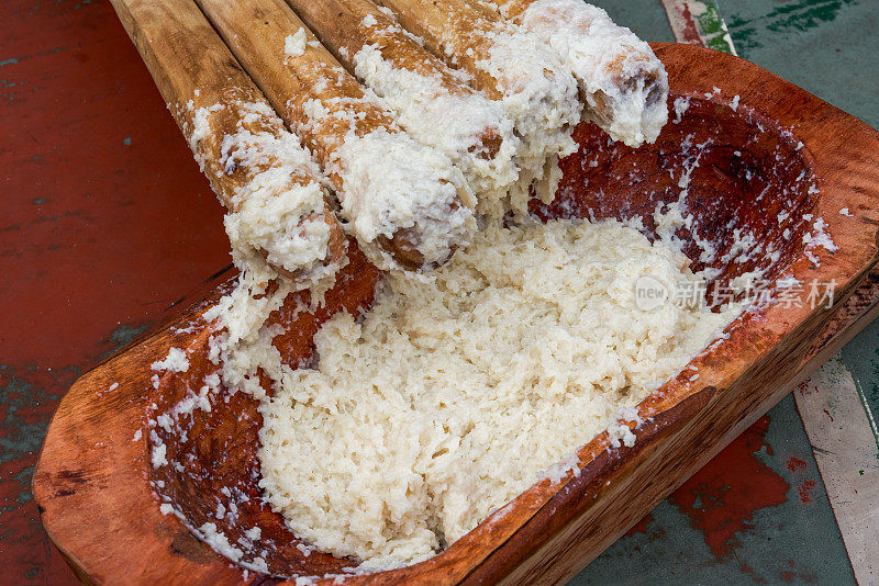 一群人用木棒敲打糯米，制作具有广西壮族特色的年糕