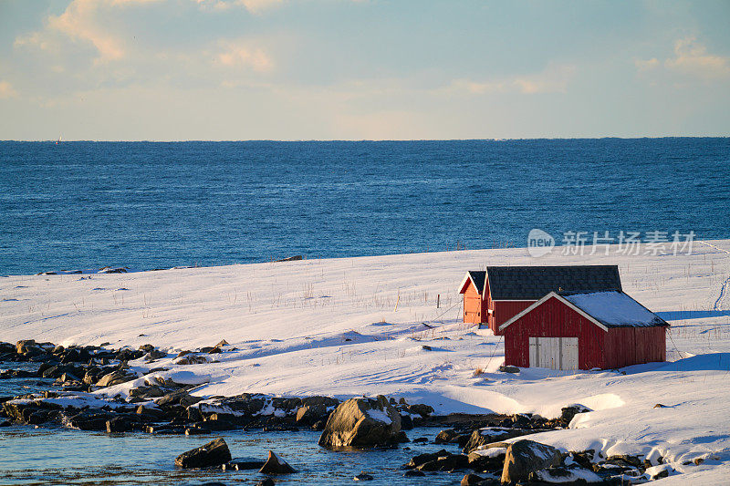 位于斯堪的纳维亚半岛挪威罗弗敦群岛的Flakstadoya岛上的Rambergstranda海滩上覆盖着雪的传统风格房屋。