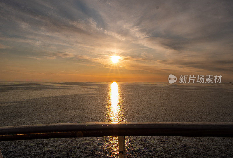 日落在海上，乌云和黑暗的天空为背景。云和地平线在海上相接。