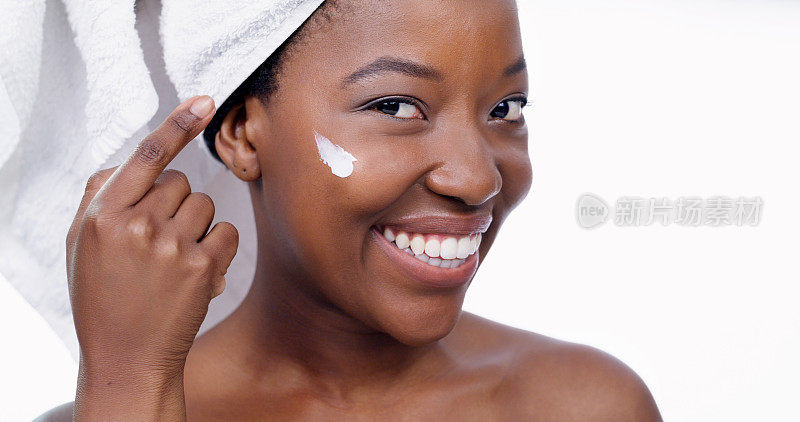 沐浴、护肤和面霜，在工作室里有黑人女性的肖像，用于产品、美容和保湿。化妆品，面部护理和水疗，化妆水在女模特的脸上隔离在白色背景