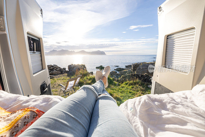 女子在她的露营车后面放松的POV在日落，海景，面包车生活概念