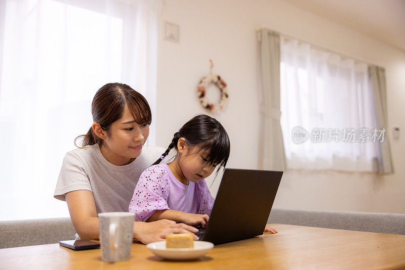 妈妈和妹妹在家里用笔记本电脑学习