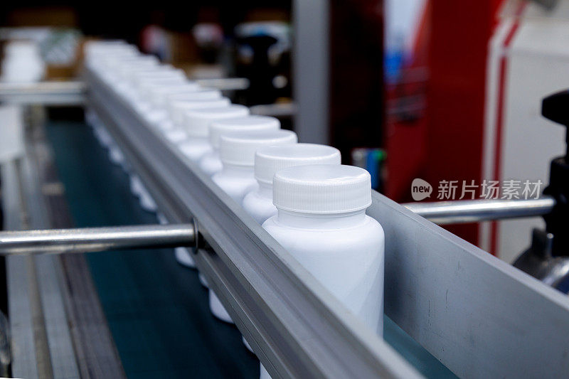 化妆品、保健品、医药生产中自动旋盖贴标机传送带上移动的白色塑料瓶。