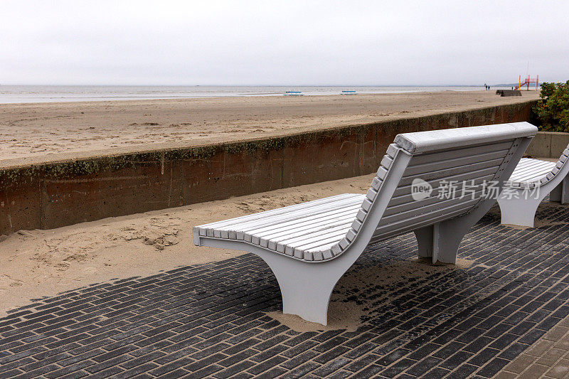 海滩岸边的白色木凳，可以看到大海