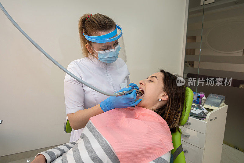 牙医医生用牙钻治疗病人的龋齿