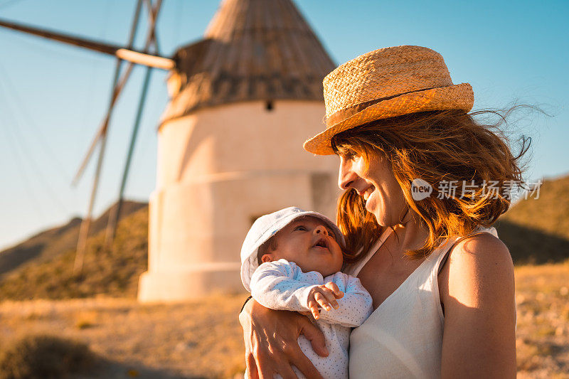 抱着新生婴儿参观古风车的游客