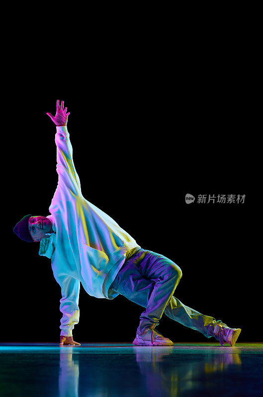 在五颜六色的霓虹灯下，年轻活泼的小伙子跳着嘻哈、霹雳舞，背景是黑色的工作室。
