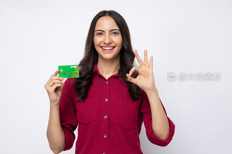 开朗的女孩穿着衬衫的肖像拿着塑料银行卡购物付款孤立在白色背景股票照片