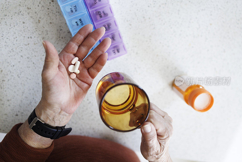 退休后吃药。老人手里拿着从每周药品整理处拿来的水杯药片。