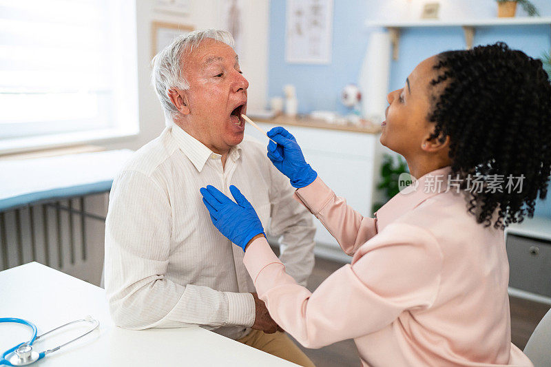 女医生黑人检查老年男性患者用压舌板治疗