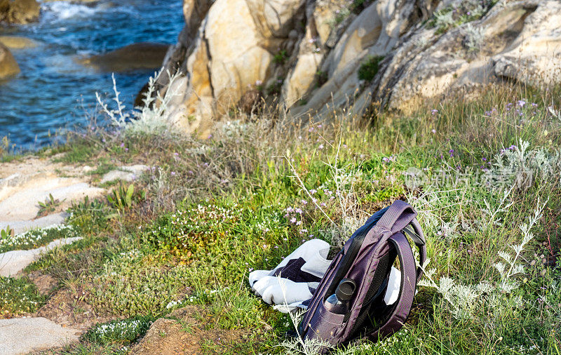 哈尔基季基上,春天在你的徒步旅行。背包和可重复使用的塑料瓶放在海滩附近的岩石上