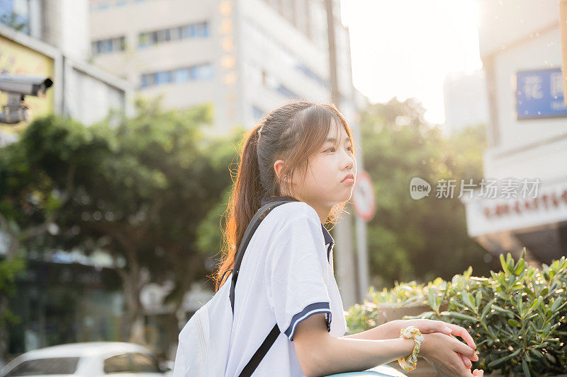 亚洲女孩背着书包在阳光下回家