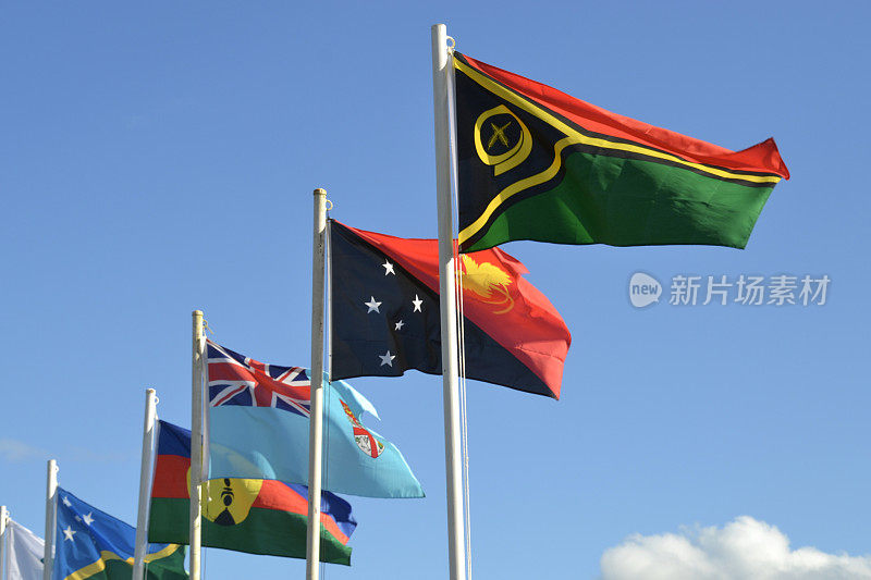 在瓦努阿图举行的一场大型足球体育赛事上，东道主瓦努阿图、巴布亚新几内亚、斐济和所罗门群岛在蓝天的映衬下悬挂了一排国旗