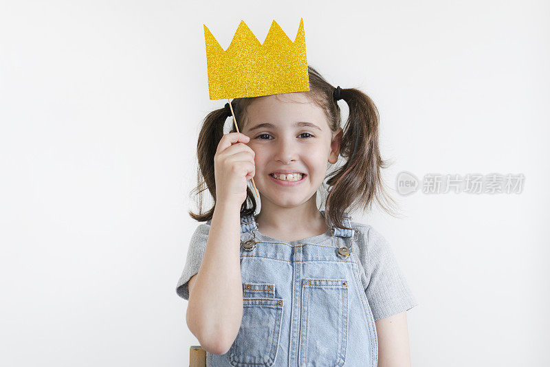 漂亮的小女孩带着纸皇冠在白色背景上摆姿势
