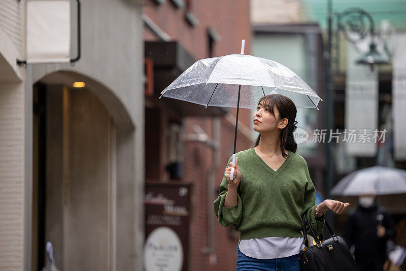 一个下雨天走在购物街上的年轻女子