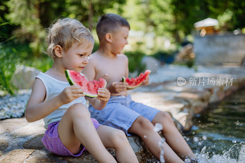 暑假，烈日炎炎，小朋友们坐在湖边吃西瓜。