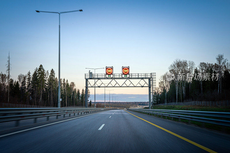 晚上空旷的多车道高速公路上的限速标志